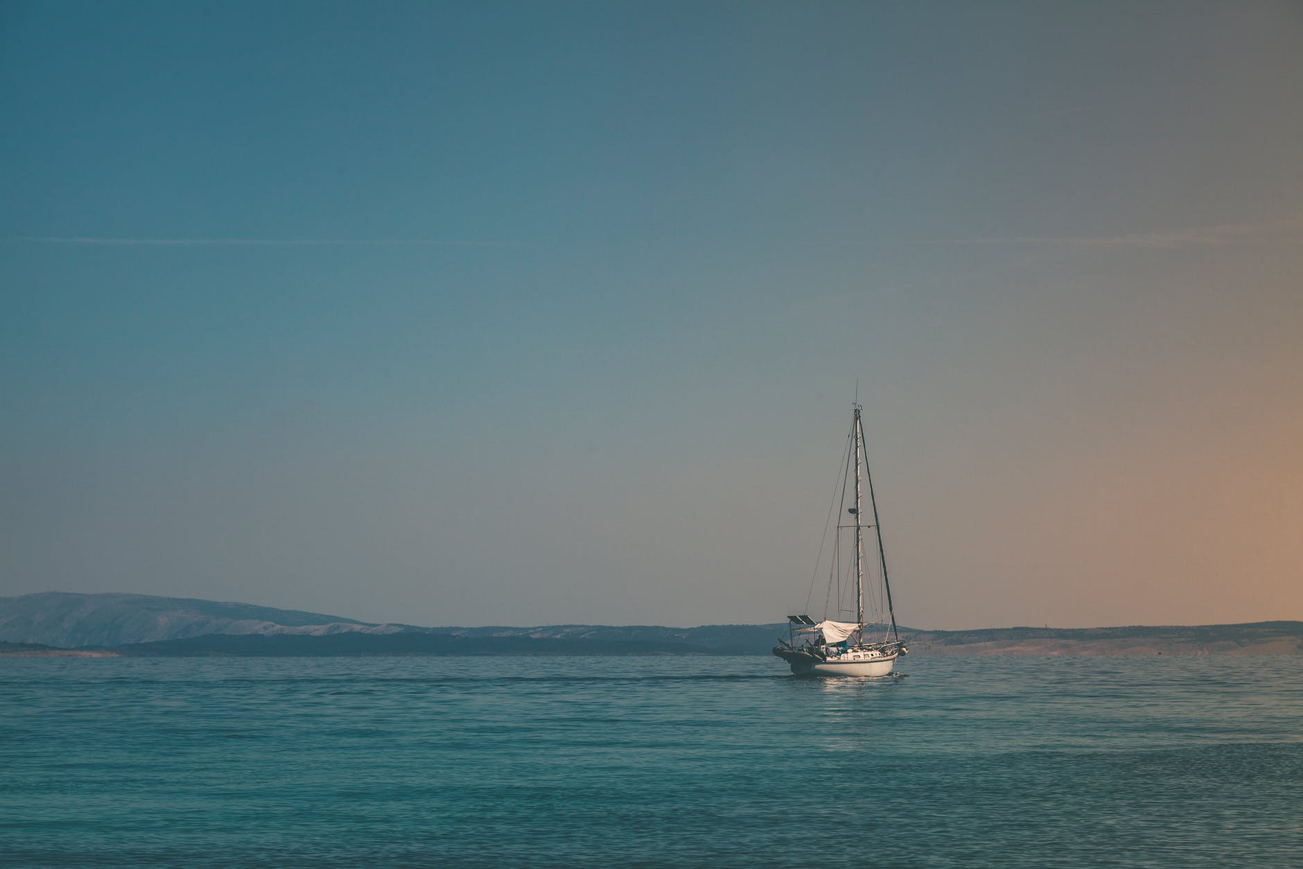 white sailboat on body of water under white sky